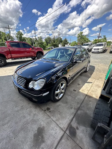 Black sedan parked outside the shop on a sunny day.